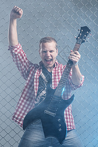年轻音乐家 有一把吉他 在栅栏背景上金属男人岩石吉他手艺术家音乐会星星歌曲音乐牛仔裤图片