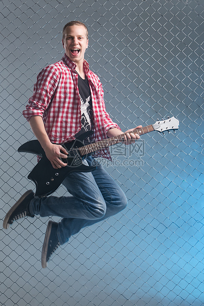 音乐 年轻的音乐家 有一把吉他在空中男性衬衫空气演员牛仔裤旋律男人栅栏摇杆岩石图片