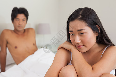 男朋友看着坐在床尾的女朋友 在看夫妻思维公寓女性膀子闲暇羽绒被家庭生活被子女士图片