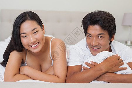 幸福的一对夫妻躺在床上感情卧室亲密感团结微笑房子软垫被子公寓男性图片