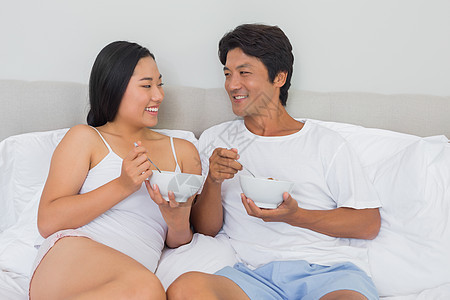 幸福的情侣在床上吃早餐勺子夫妻女士微笑快乐休息睡衣男朋友家庭生活男性图片