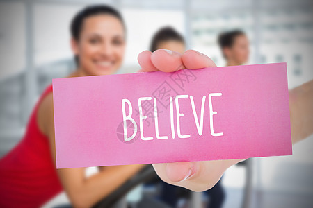 女人拿着粉红卡说相信纺纱运动粉色健身室运动服一个字微笑身体护理信仰图片