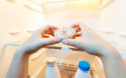 女用手从冰箱里拿甜甜圈的照片图片