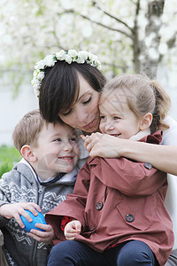 母亲和两个孩子拥抱在开阔的花园中兄弟家庭季节男生幸福闲暇妈妈母性女孩姐姐图片