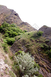 山蓝色爬坡石头天空阴影绿色植物岩石灰色衬套图片