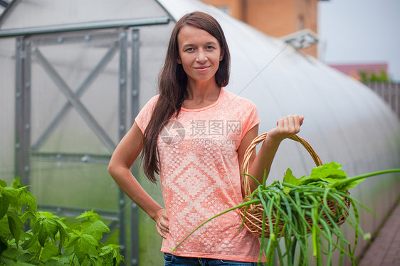 在温室里拿着一篮绿菜和洋葱的年轻女子花园蔬菜收成女孩农民营养沙拉食物叶子农场图片