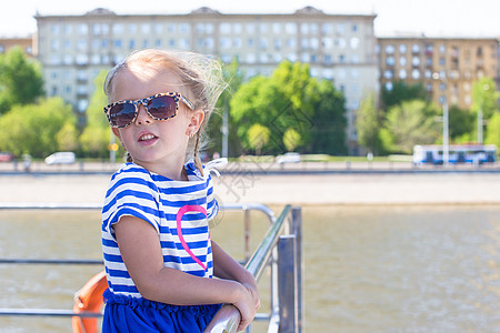 在大城市航行的船甲板上 可爱的小可爱女孩游艇孩子闲暇运动幸福享受巡航栏杆乐趣水手图片