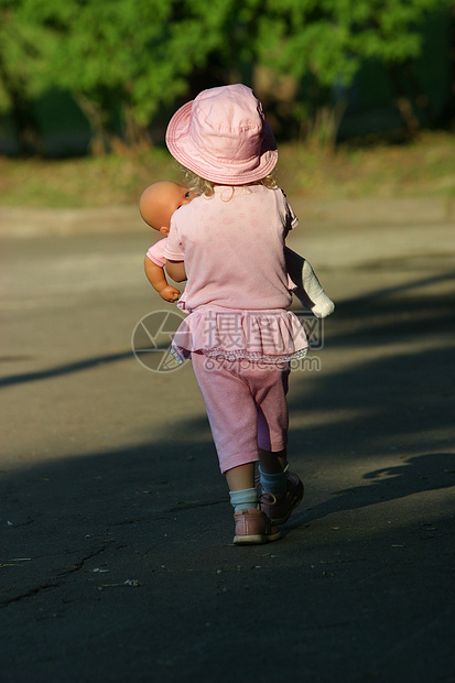 带着娃娃的女孩阴影公园假期孩子童年粉色玩具太阳图片