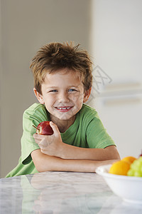 在厨房里拿着苹果的年轻男孩图片