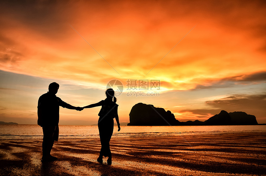 浪漫情侣在海滩日落时握手海洋女性夫妻男性阳光天空旅行蜜月假期太阳图片