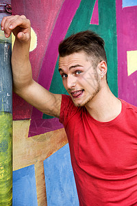 金发英俊的年轻男子 对抗色彩多彩的涂鸦墙壁青少年乐趣男生城市舌头成人男人头发街道男性图片
