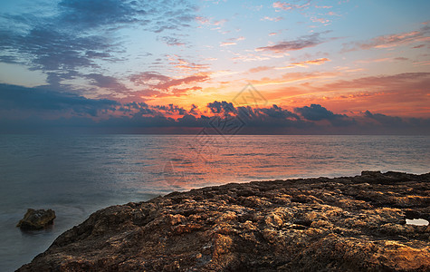 日落时落的洛基海滩地平线场景旅行石头橙子海浪海洋风景海岸日落图片