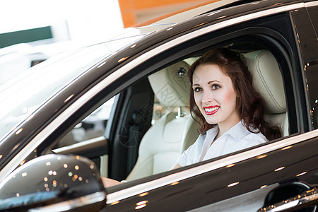 女青年在展厅的新车里手指乐趣微笑发动机司机女孩人士女士旅行驾驶图片