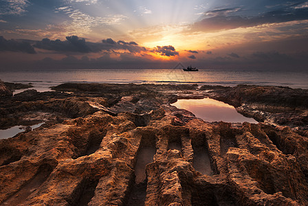 日落在海面上海洋旅行反射石头海景橙子水池射线太阳海浪图片