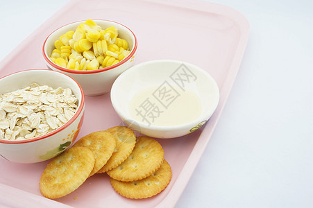玉米燕麦饼干和粉红色托盘上的甜奶图片
