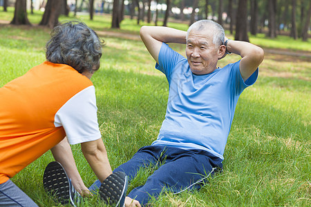 年老祖父在公园做仰卧起坐退休女士太阳运动装活力森林训练夫妻手臂手势图片