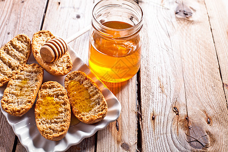 盘子里的饼干和蜂蜜营养陶瓷面包勺子乡村木头玻璃小吃垃圾食物图片