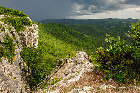 暴风雨前享受旅行单身上坡峡谷岩石双手悬崖顶峰绿色图片