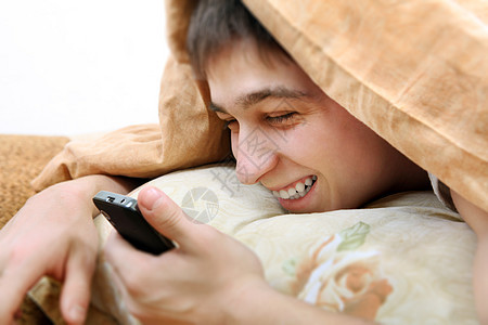 带手机的青少年男性细胞电话被单工具毯子说谎枕头房间喜悦图片