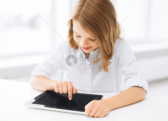 在学校里带着平板电脑的笑笑小女孩桌子孩子青少年互联网家庭作业玩家课堂技术上网电子书图片