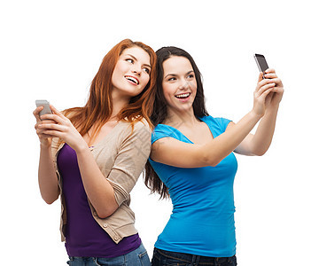 两个带着智能手机的笑笑青少年友谊学生娱乐拍照短信微笑幸福乐趣互联网图画图片