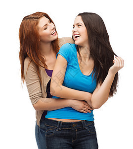 两个笑笑的女生 互相看着对方白色乐趣青年学生队友衣服拥抱闺蜜友谊女性图片
