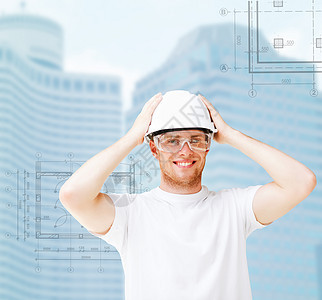 戴着安全眼镜的白头盔男建筑师摩天大楼风镜微笑安全城市方案承包商绘画技术员蓝图图片
