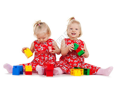 两个身穿红裙子的双胞胎女孩 玩砖块游戏连衣裙家庭孩子女儿们活动玩具女性幼儿园立方体兄弟姐妹图片