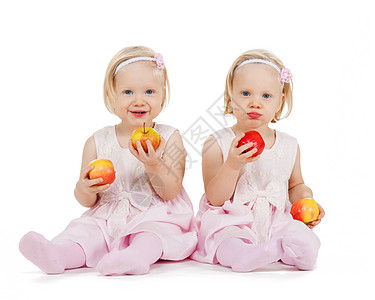 两个完全相同的双胞胎女孩玩苹果游戏微笑活力幼儿家庭地面婴儿食物女孩们兄弟姐妹姐姐图片