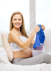 开启礼物盒的孕妇笑着微笑母性开襟衫惊喜淋浴新生说谎幸福孩子肚子腹部图片