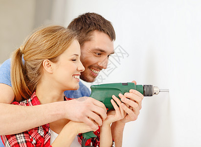 在家里墙上闪着微笑的对夫妇钻洞帮助家庭男人工作安全成人夫妻教学木工维修图片