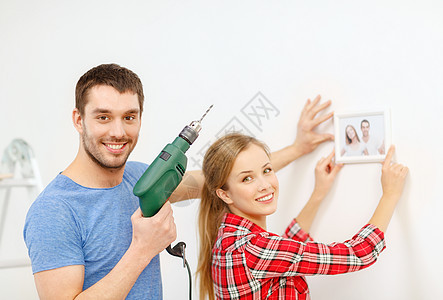 在家里墙上闪着微笑的对夫妇钻洞成人改造照片装修工作工具团队框架便利教学图片
