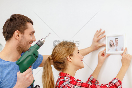在家里墙上闪着微笑的对夫妇钻洞钻头男人照片木工框架改造便利帮助装修房子图片