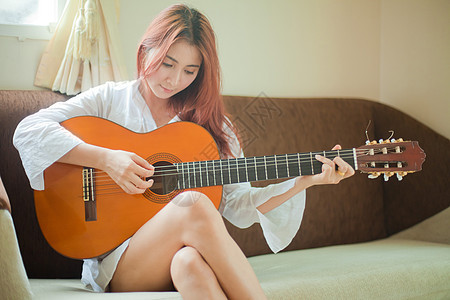 年轻妇女弹吉他女孩吉他手歌手乐趣头发房间女士白色音乐家音乐图片