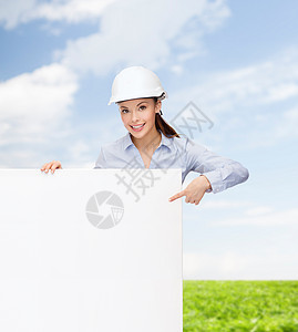 戴头盔的女商务人士用手指对着板承包商天空建筑学女性成人拉丁木板广告建筑工程师图片