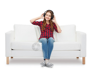 坐在沙发上戴耳机的女童音乐快乐歌曲长椅女士音乐播放器青年女性热情说谎图片