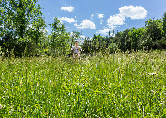 在草原上 高年男子在零转折草坪的草坪割草机图片