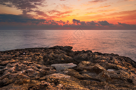 日落时落的洛基海滩海岸地平线岩石天空场景风景旅行海浪海洋石头图片
