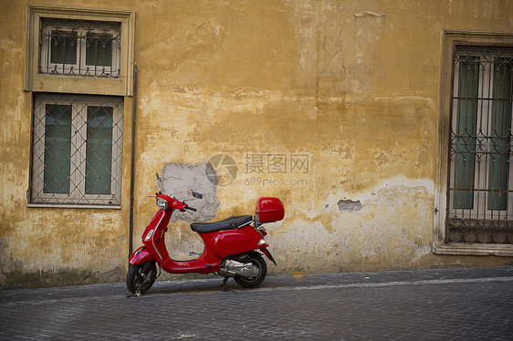 一辆城市街道上明亮的红色Vespa小摩托车图片