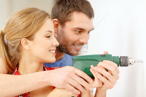 在家里墙上闪着微笑的对夫妇钻洞建筑女士成人夫妻教学钻头男人木匠团队工具图片