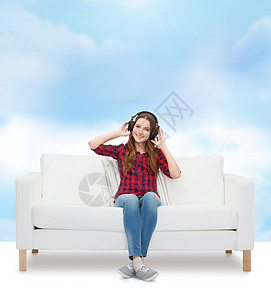 坐在沙发上戴耳机的女童成人女孩微笑播客女性快乐说谎歌曲打碟机幸福图片