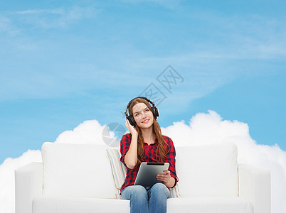 用耳机和平板电脑坐在沙发上的女孩青少年幸福药片技术收音机天空长椅互联网女士立体声图片