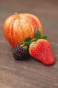 木质表面的多汁苹果 黑莓和草莓图片