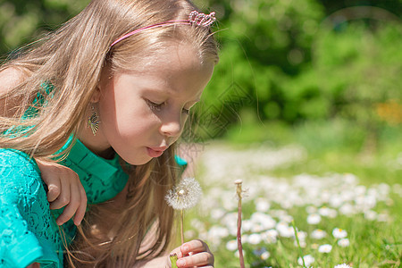可爱小女孩的肖像 在花园里吹一头花朵行动喜悦编织草地头发童年女孩金发女郎情感乐趣图片