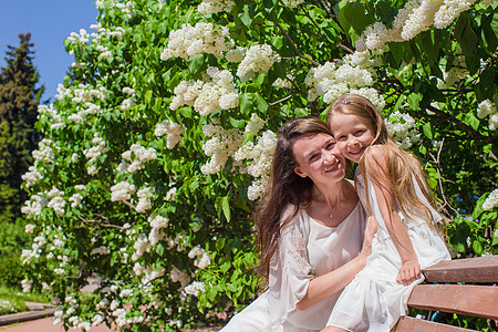 快乐的妈妈和可爱的姑娘 在红花花园享受温暖的一天女士婴儿女性孩子家庭父母女儿母亲公园樱花图片