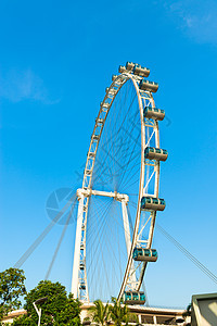 蓝色天空下的摩天轮圆形圆圈滚筒吸引力旋转木马天空车轮公园传单绿色图片