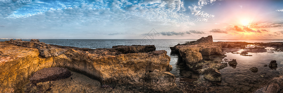 太阳用古老的废墟日落在海和洛基海岸上空海岸海洋石头支撑橙子海滩海浪地平线场景岩石图片