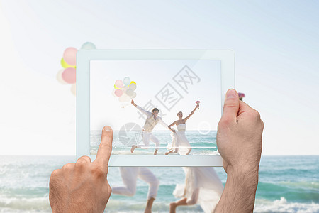 手握平板电脑的复合图像c花束婚姻乐趣海岸线金发海滩夫妇触摸屏开端新郎图片