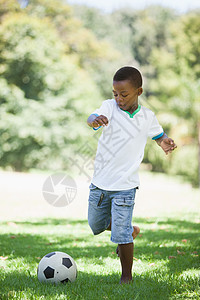 小男孩踢橄榄球 在公园踢足球图片