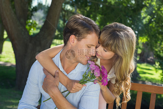 可爱的一对夫妇拥抱在公园里 女孩拿着鲜花抱着花图片
